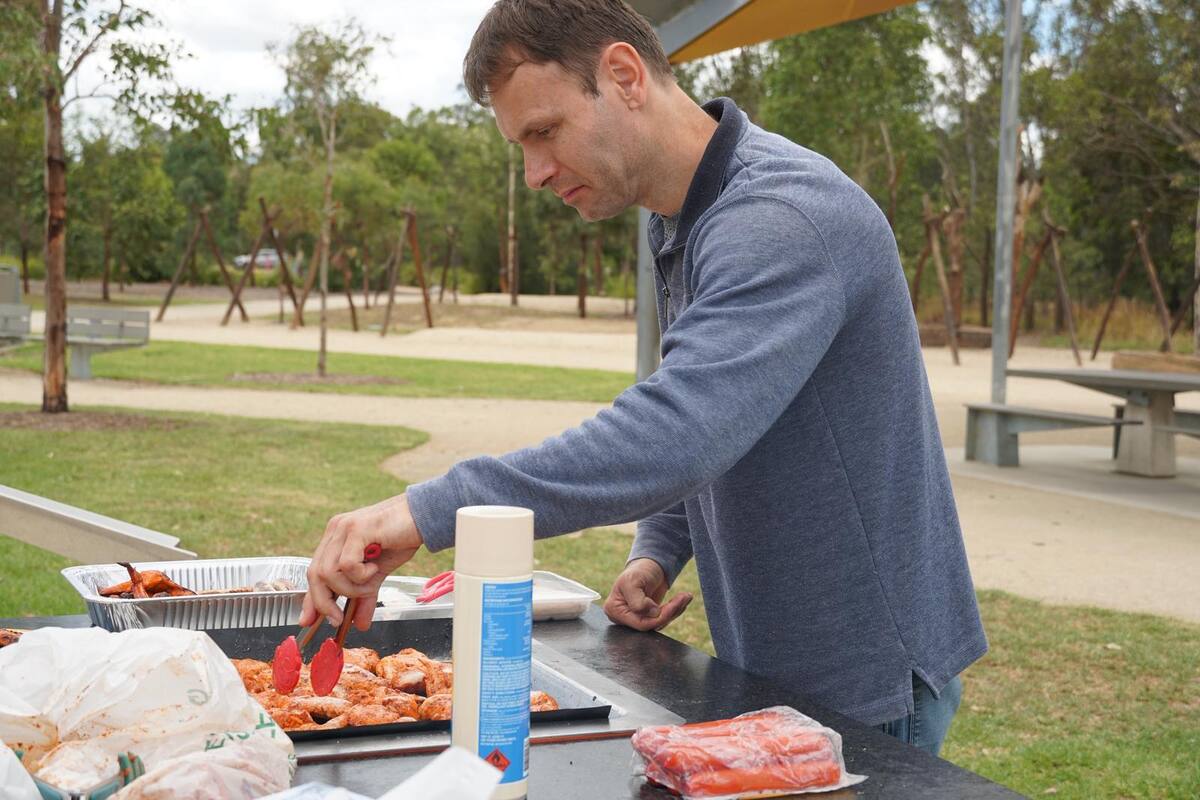 A man preparing a barbecue lunch outdoors during an Enable Hub community outing