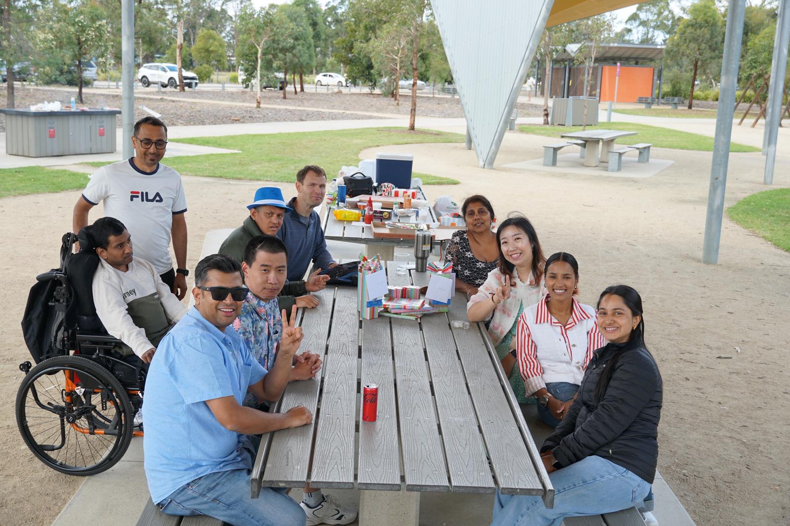 A large group of Enable Hub participants, support workers and family members enjoying a community picnic together